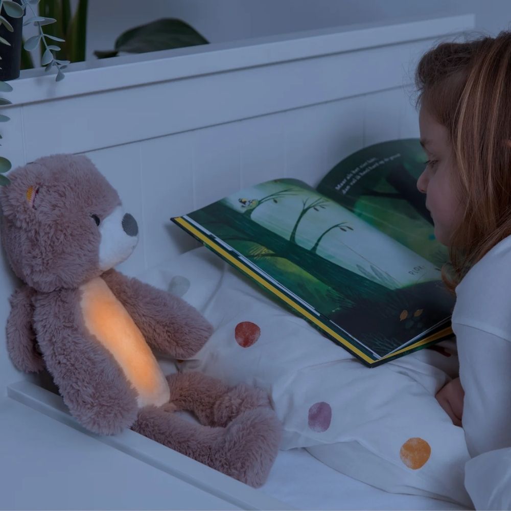 Little girl reading with Brody the Bear. Yellow light means stay in your room a little longer.