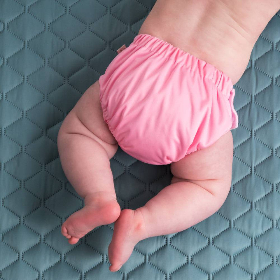 Baby wearing a pink diaper on a textured blue surface