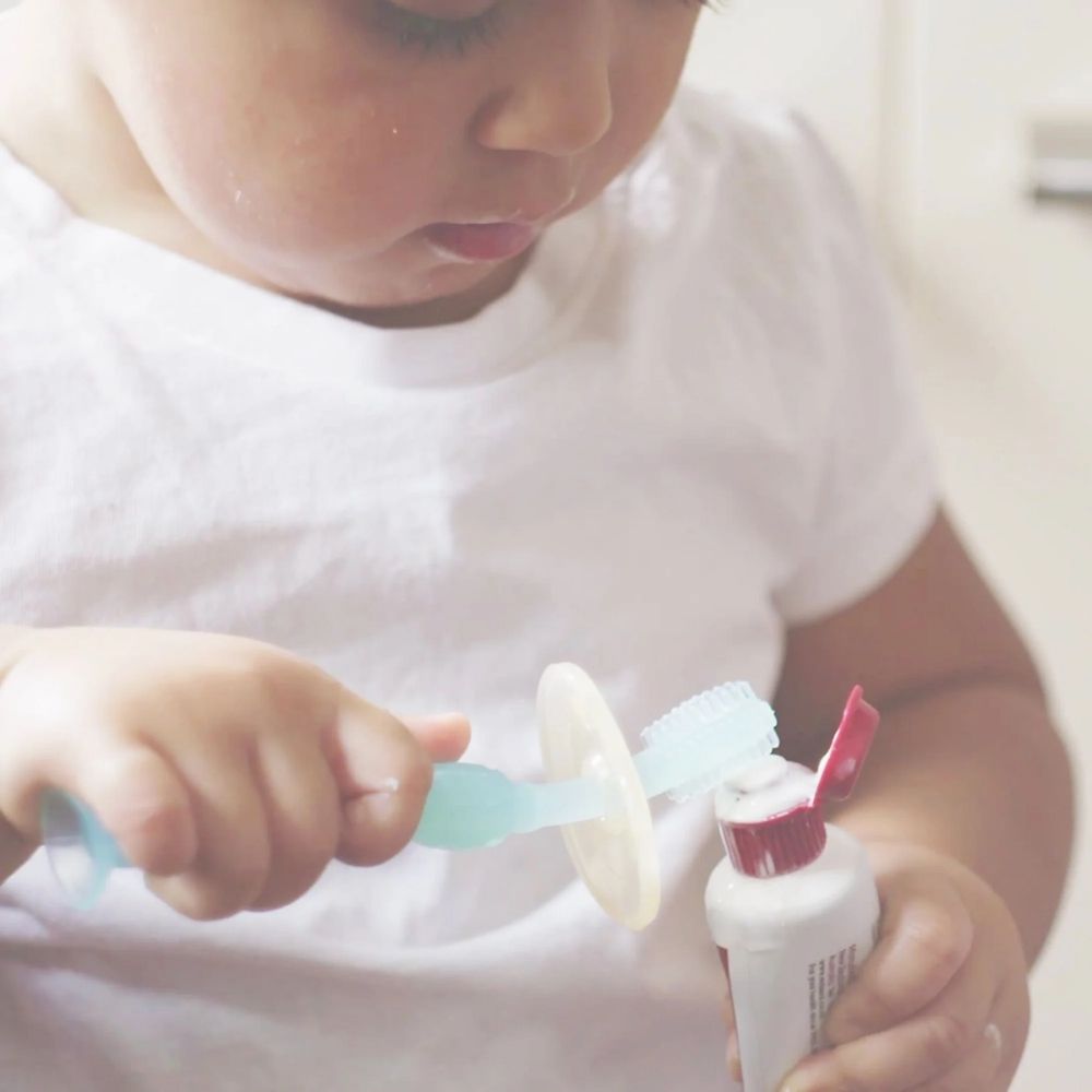 Baby putting toothpaste on the Haakaa 360 Toothbrush