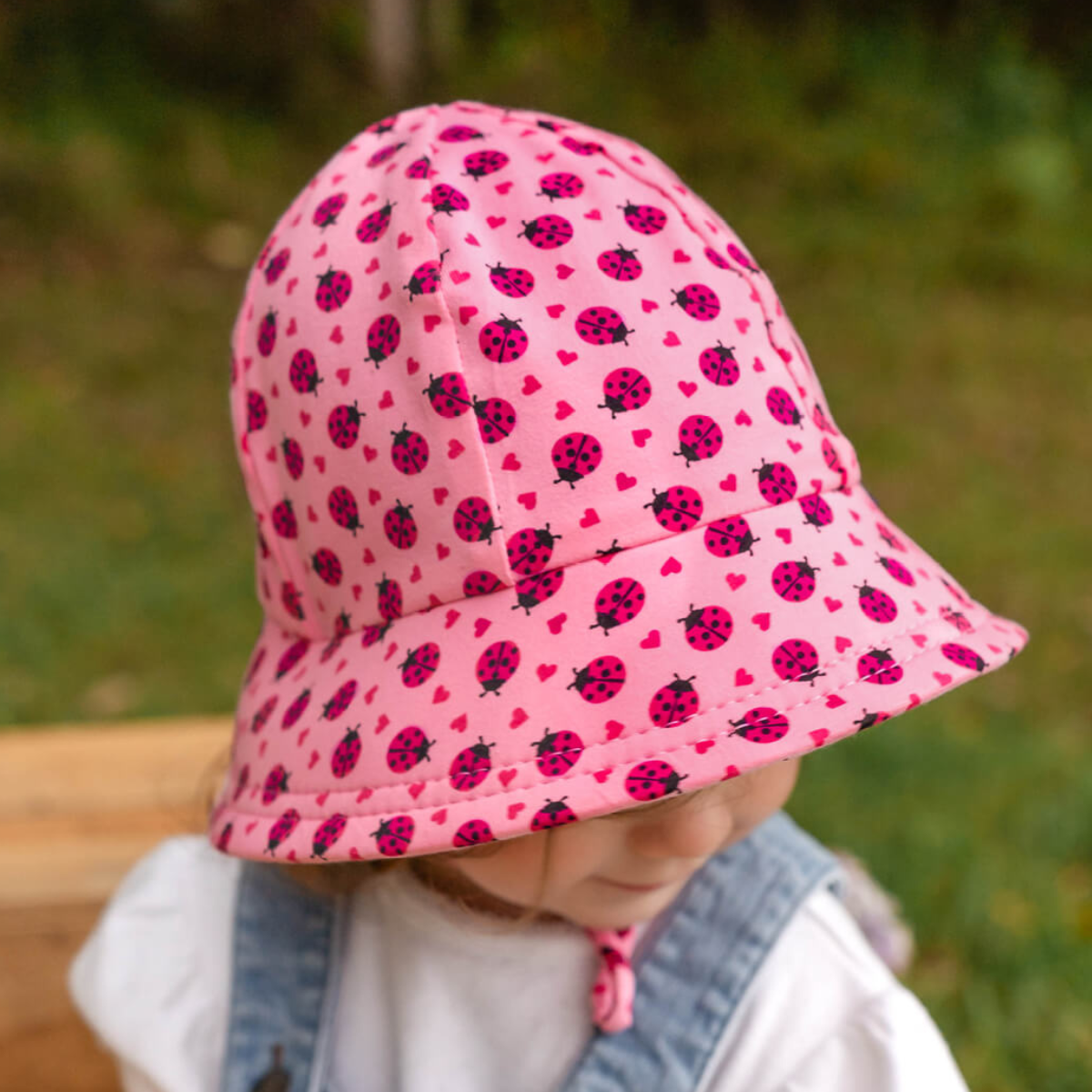 Child wearing a pink sun hat with ladybug pattern outdoors