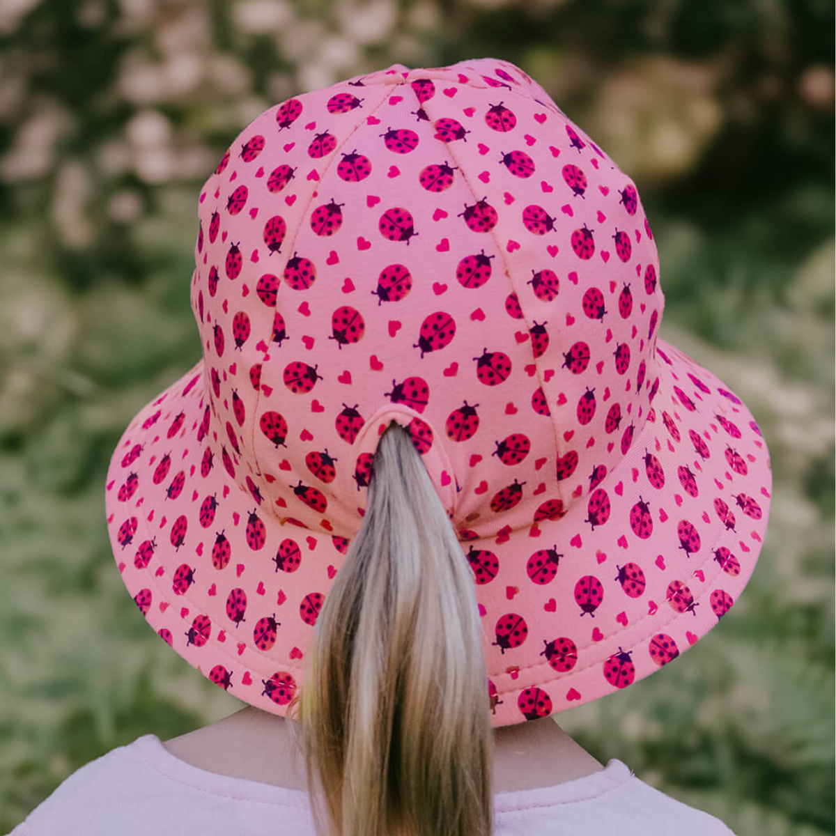 Person wearing a pink bucket hat with ladybug pattern outdoors