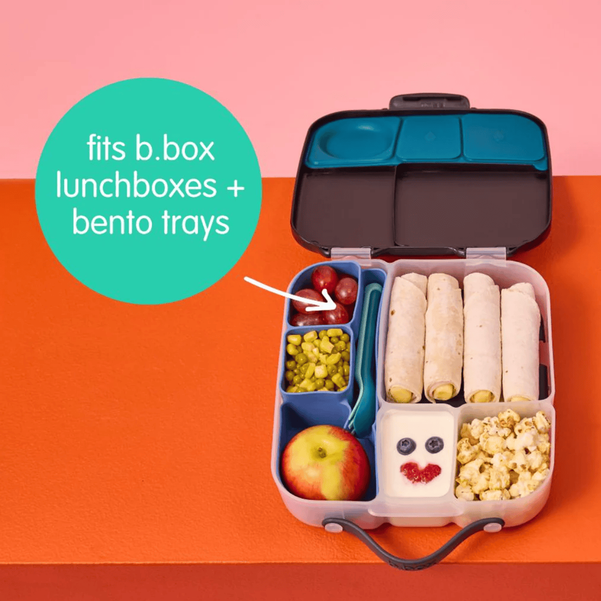 Bento box with compartments filled with food on a pink and orange background