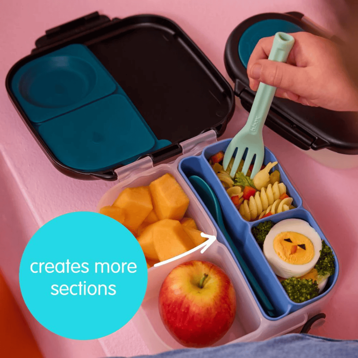 Bento box with compartments filled with food on a pink background
