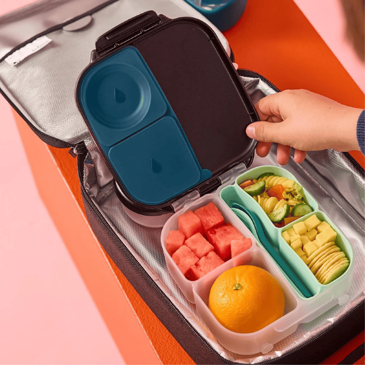 Bento box with compartments containing fruits and vegetables on a colorful background