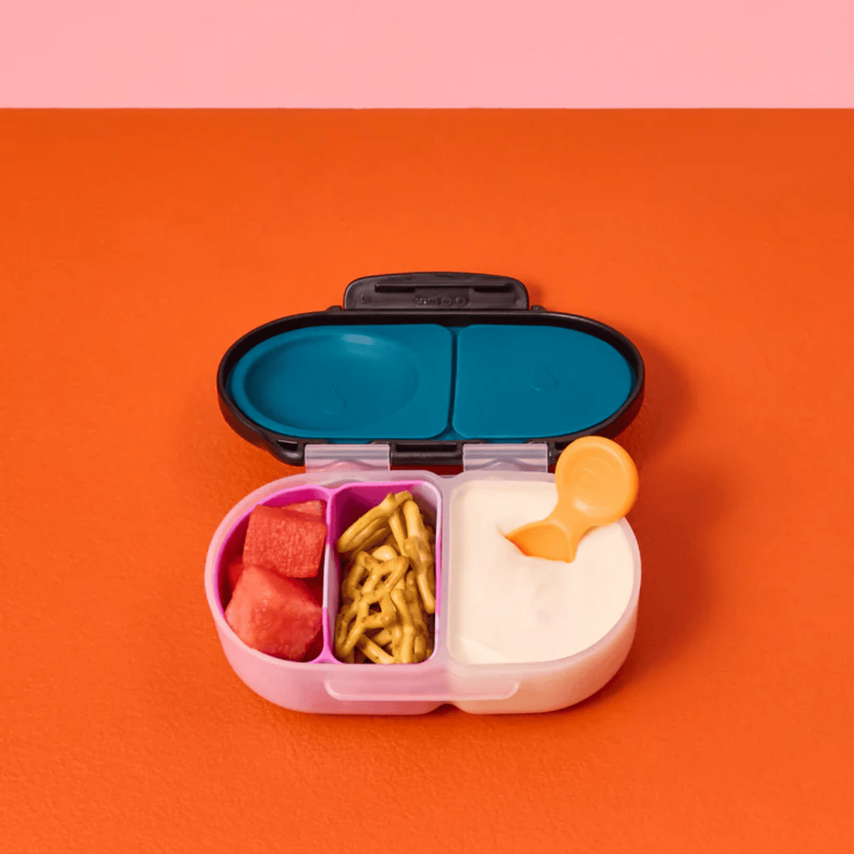 Colorful bento box with compartments containing food on a pink and orange background