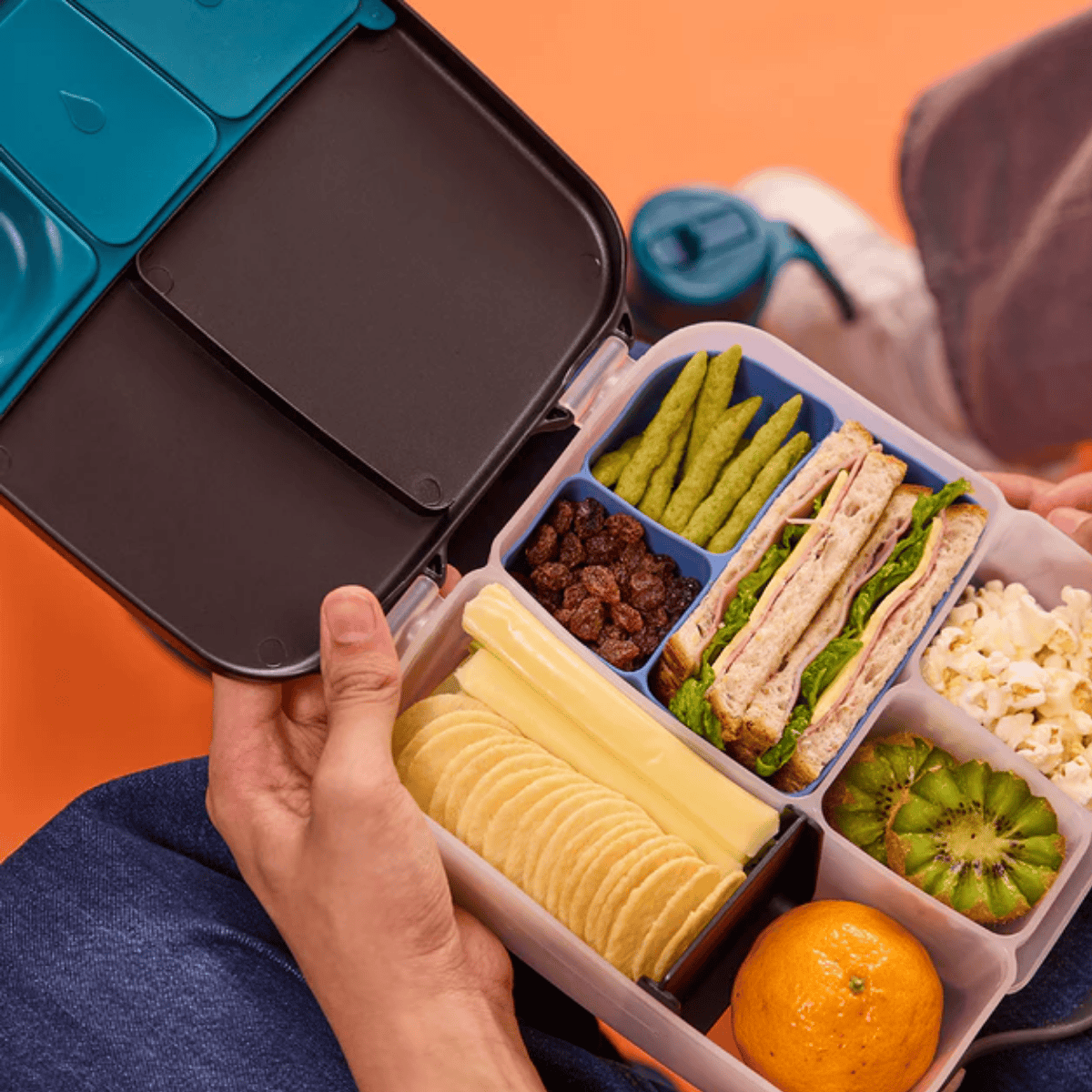 Bento box with compartments containing various food items on an orange background
