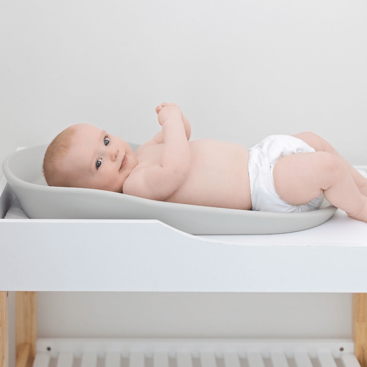 Baby lying on a changing table with a white background