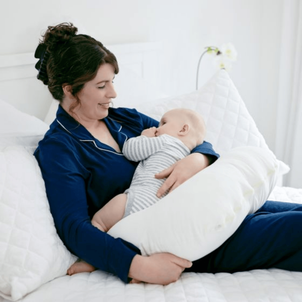 Woman in blue pajamas holding a baby in bed