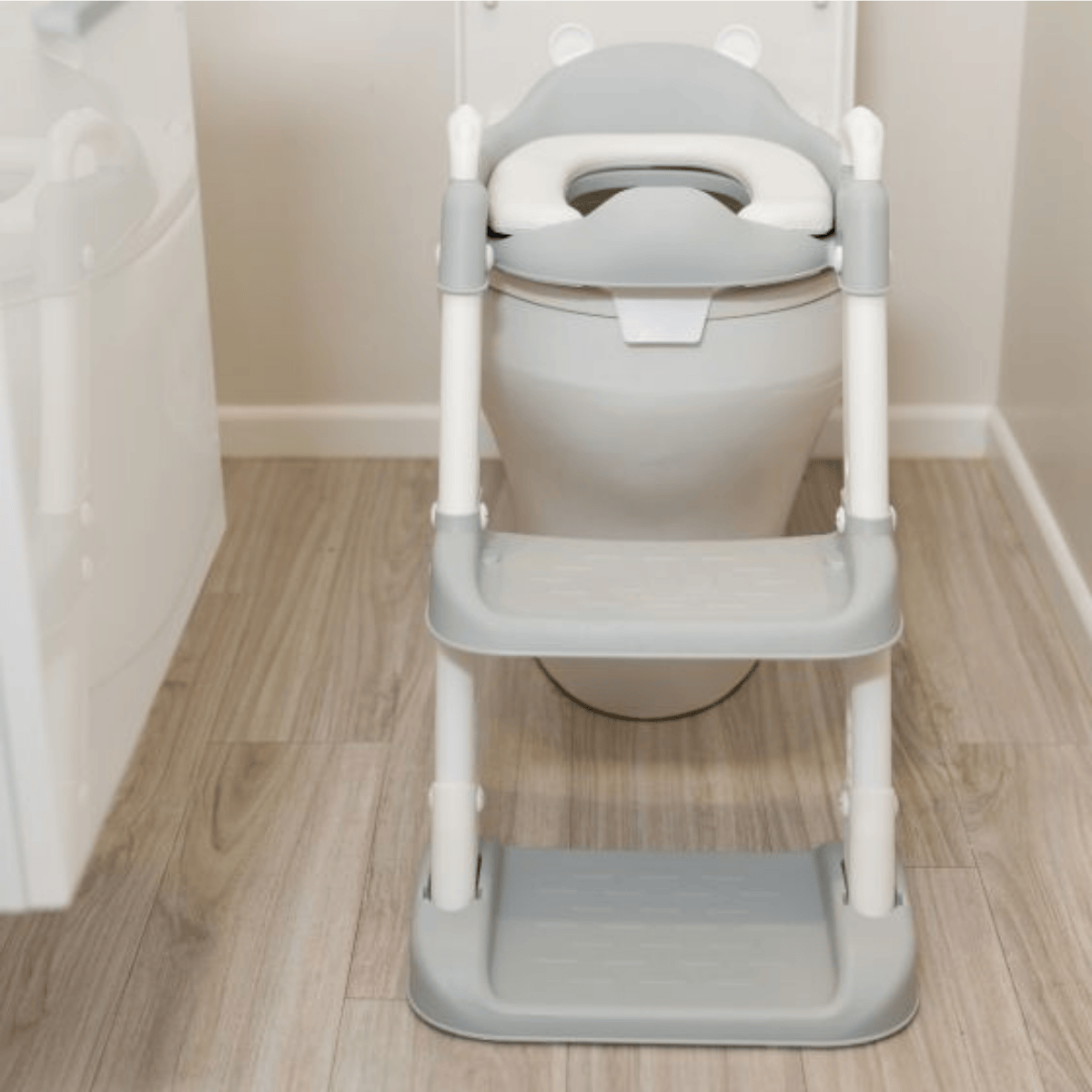 Children's toilet training seat with step stool on a wooden floor.