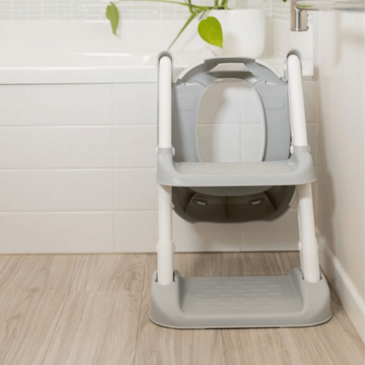 Children's toilet training seat with step stool on a wooden floor.
