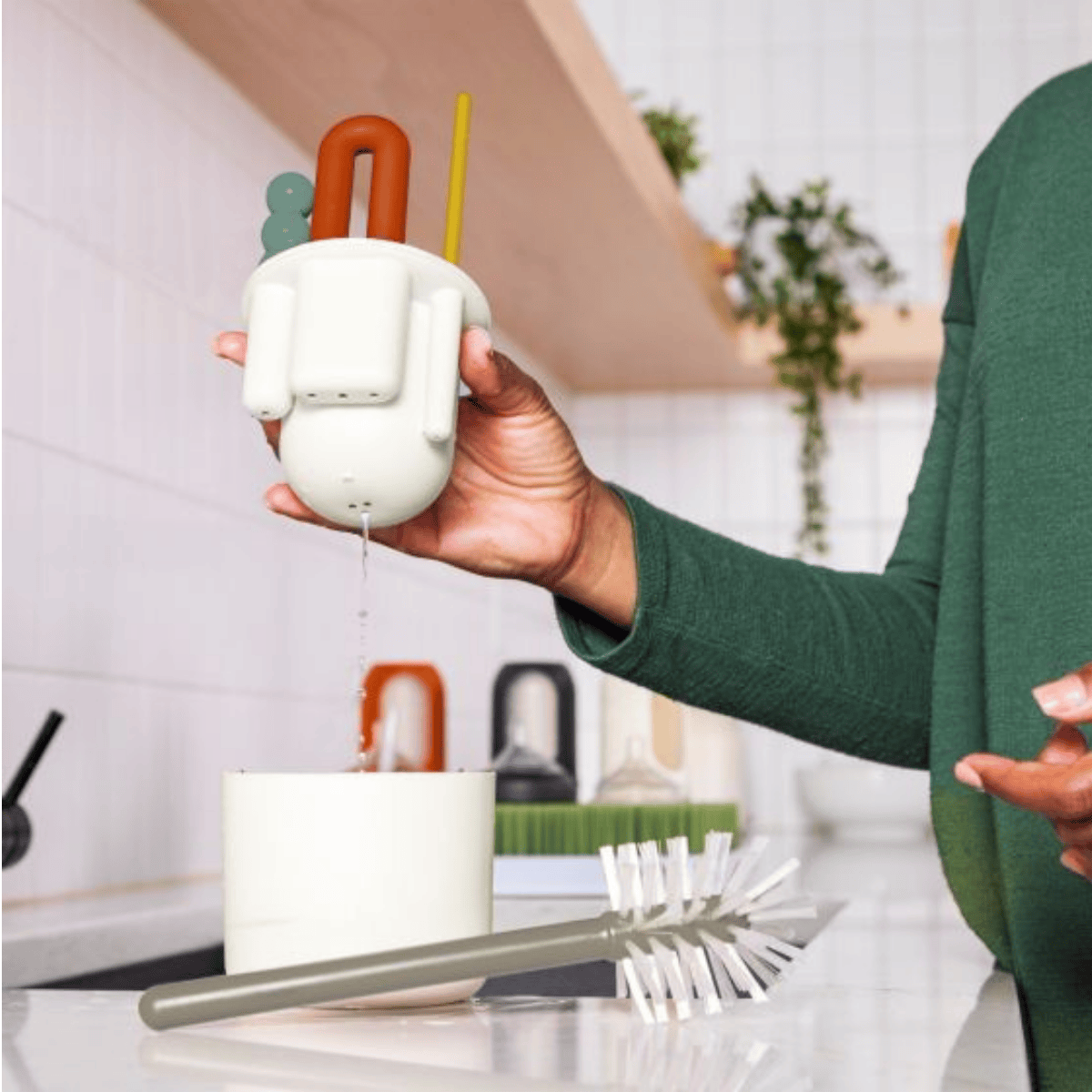 Person holding a white silicone straw with colorful accents in a kitchen setting