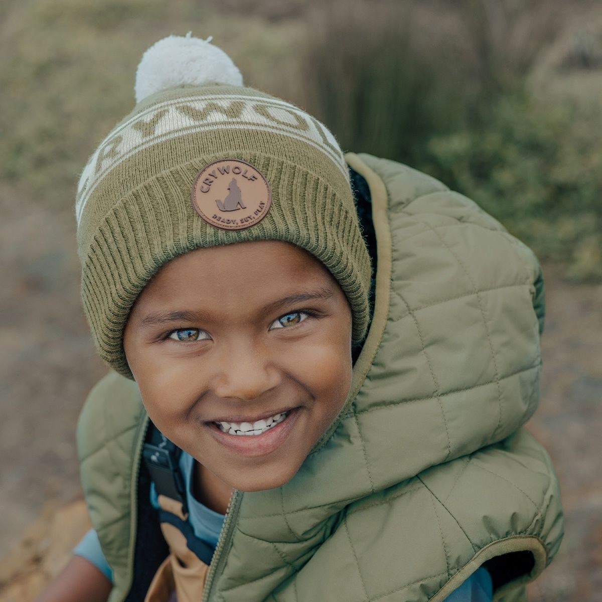 A boy outside wearing the Crywolf Beanie in fern colour.