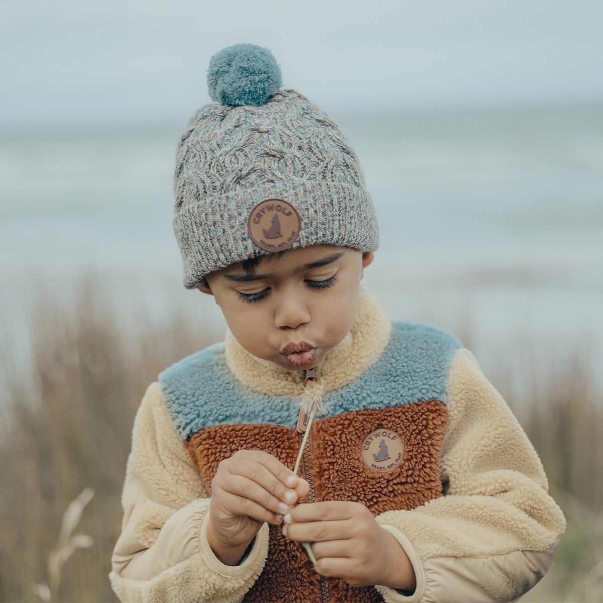 A boy wearing the blue speckled beanie outside in the cold.