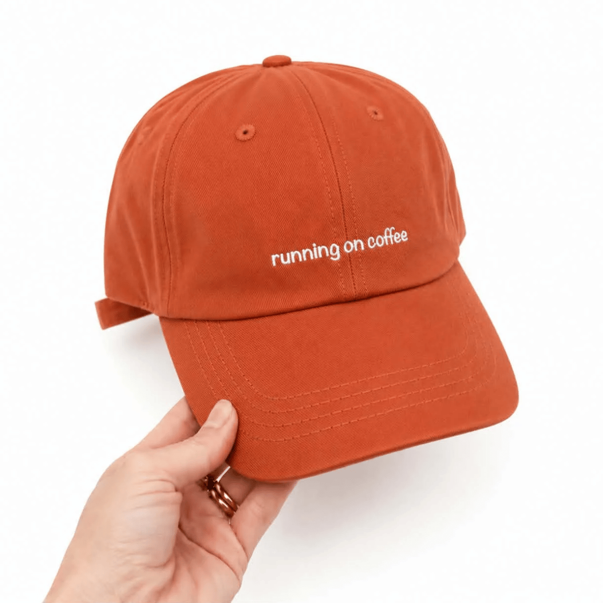 Cotton baseball cap in Orange with the words 'running on coffee' on it. 