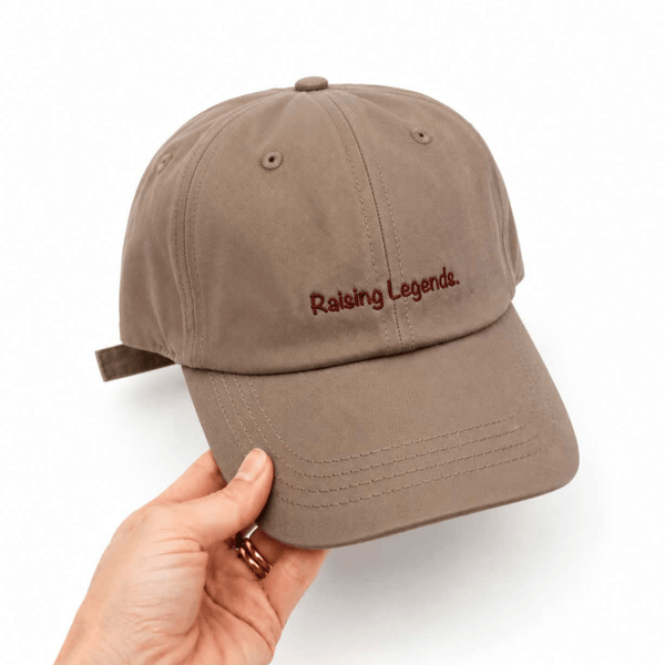 Cotton baseball cap in brown with the words 'raising legends' on it. 