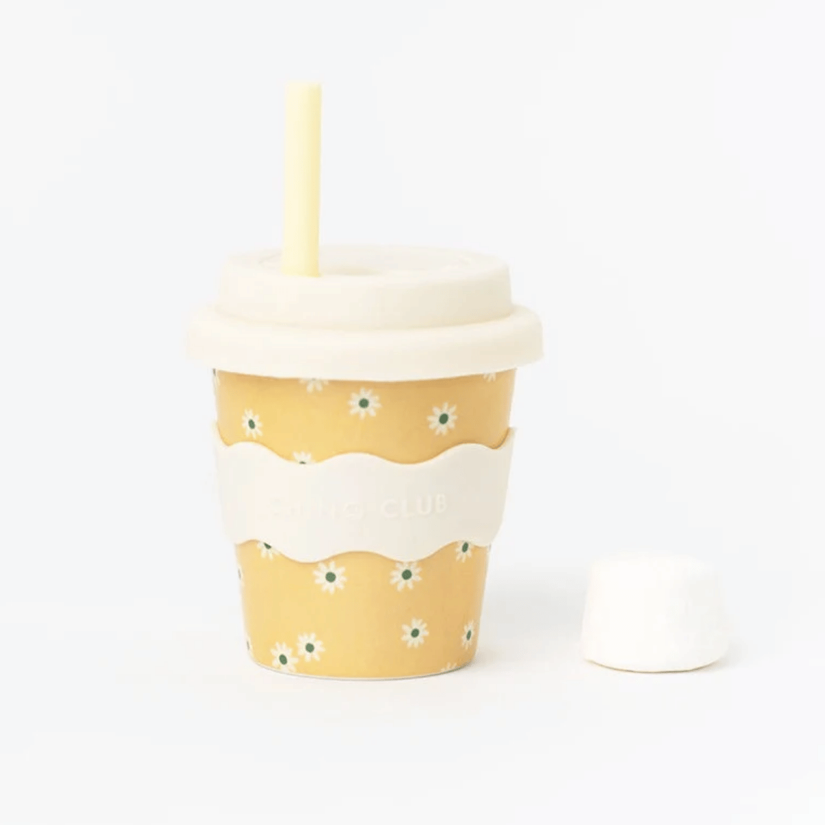 A reusable fluffy cup with a yellow floral pattern, a white silicone sleeve, a cream lid, and a pale yellow straw, shown on a clean white background with the lid removed and placed beside the cup.