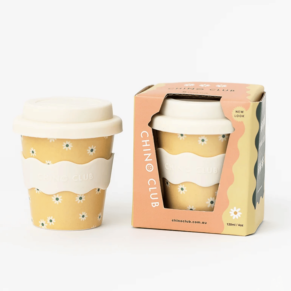 A reusable fluffy cup with a beige lid and a white wavy sleeve printed with small white flowers, shown next to its peach and beige branded box on a clean white background.