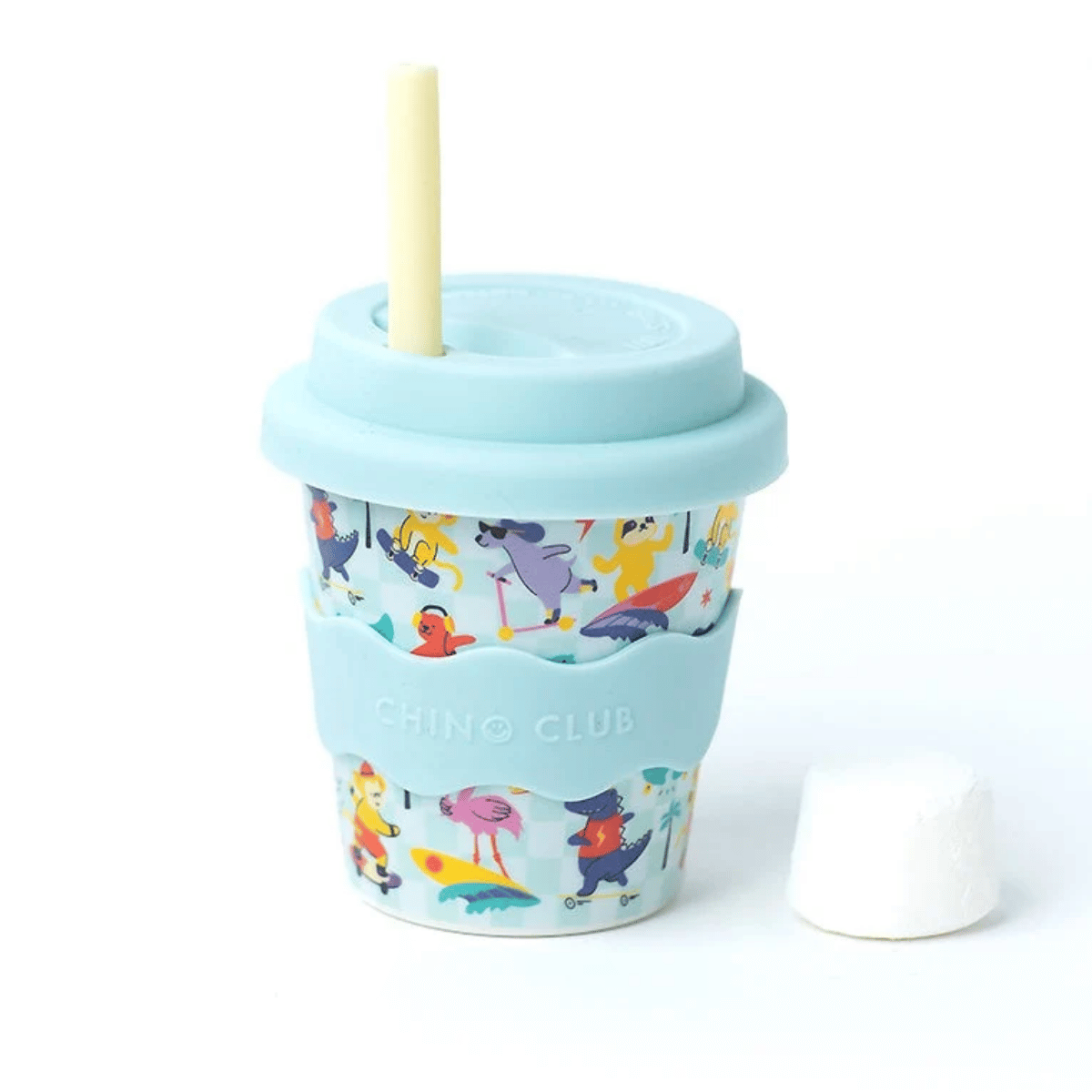 A reusable travel tumbler with a light blue lid and straw, featuring a colorful cartoon animal print and a light blue silicone sleeve with the brand name 'CHINO CLUB' embossed. A small white condiment cup is placed beside it on a clean white background.