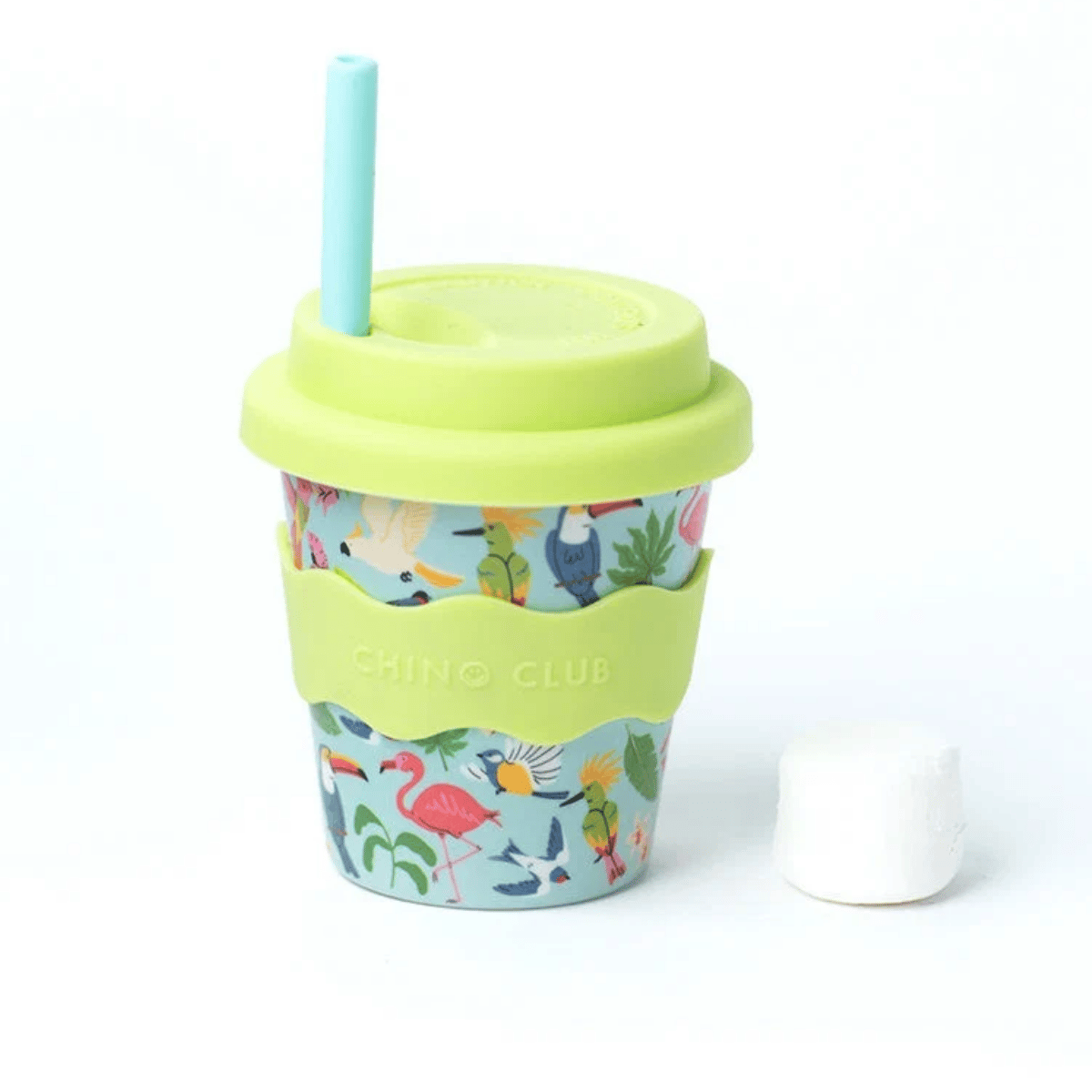 A reusable travel tumbler with a light blue straw, lime green lid and sleeve, and a tropical bird and flamingo print on a light blue background. A white marshmallow sits to the right on a clean white background.