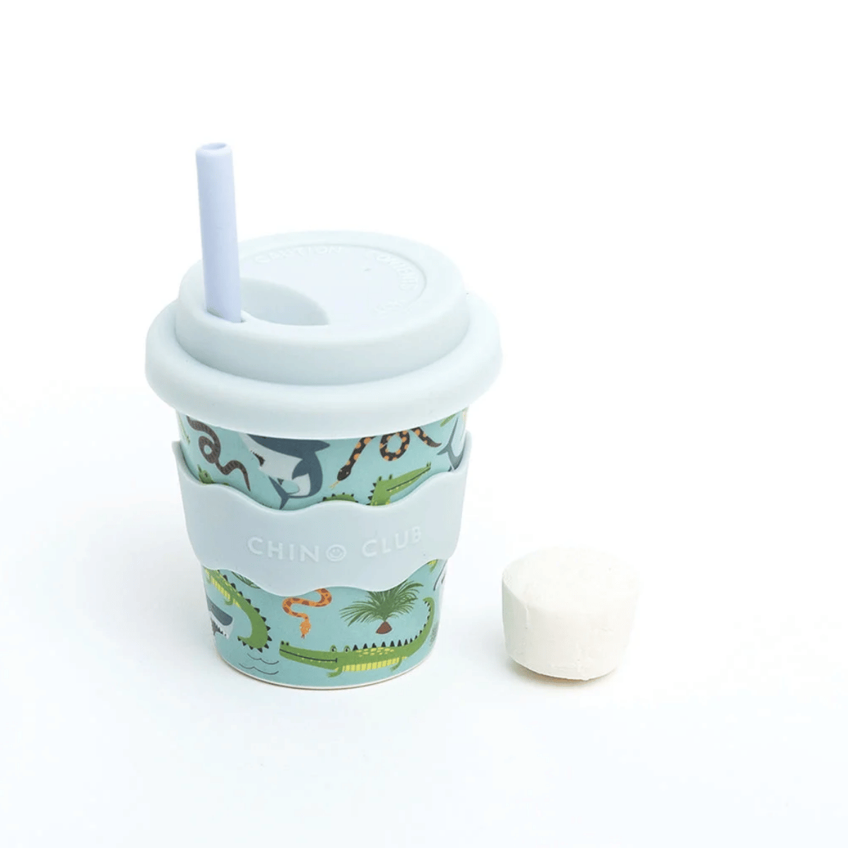 A reusable travel tumbler with a light blue lid and straw, featuring a colorful dinosaur and crocodile illustration pattern on a mint green background. It has a light blue silicone sleeve with the brand name 'CHINO CLUB' printed on it.
