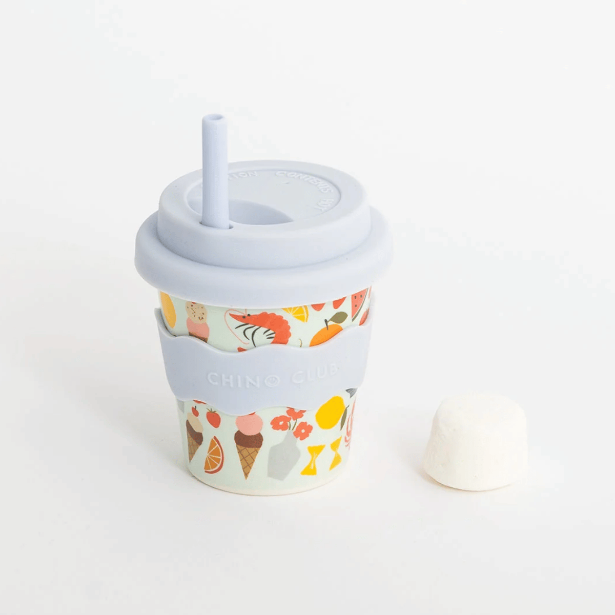A reusable  travel tumbler with a light blue lid and straw, featuring a pastel multicolor ice cream and fruit pattern and a matching light blue silicone sleeve. The tumbler is shown on a clean white background with its white lid placed beside it.