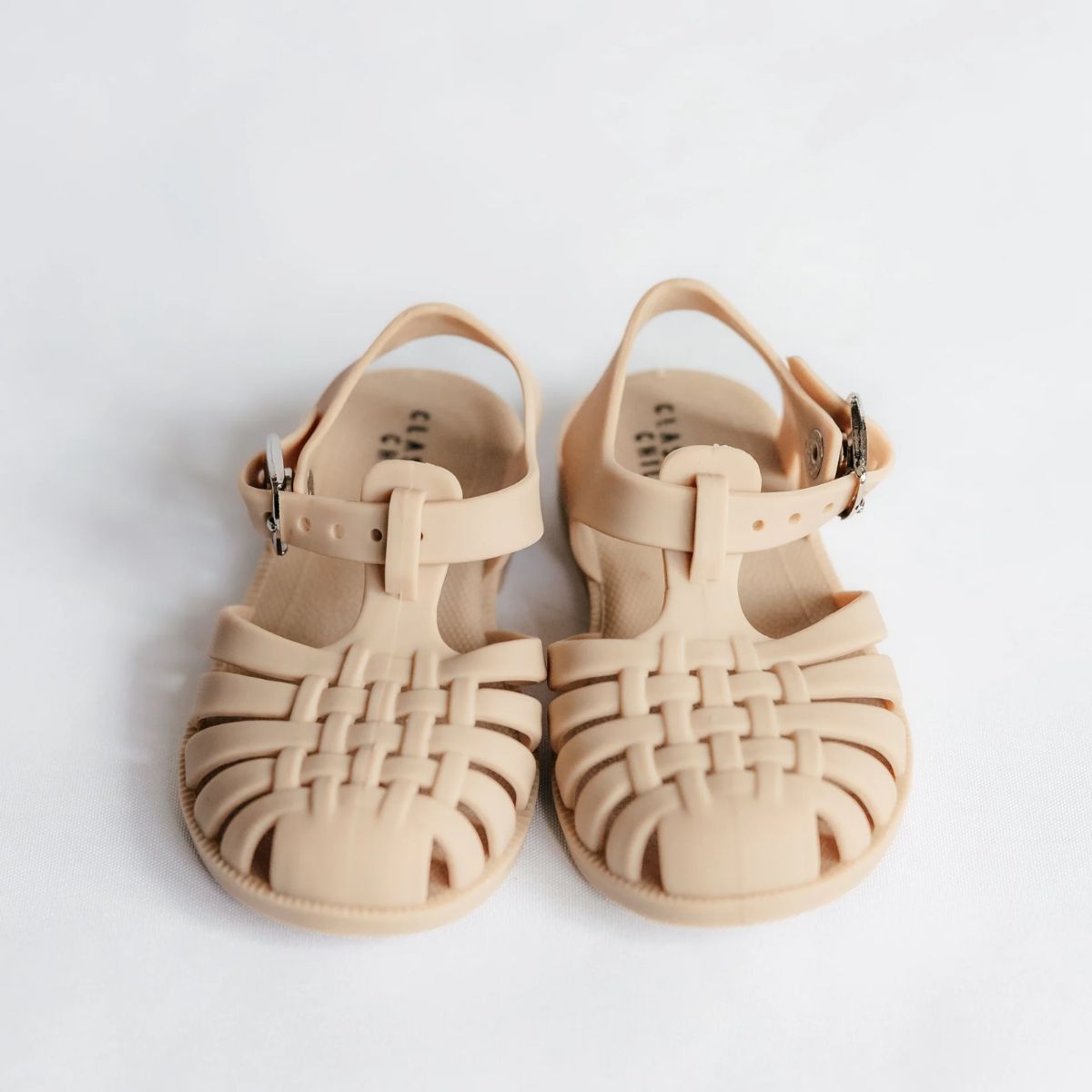 Pair of beige sandals on a light gray background