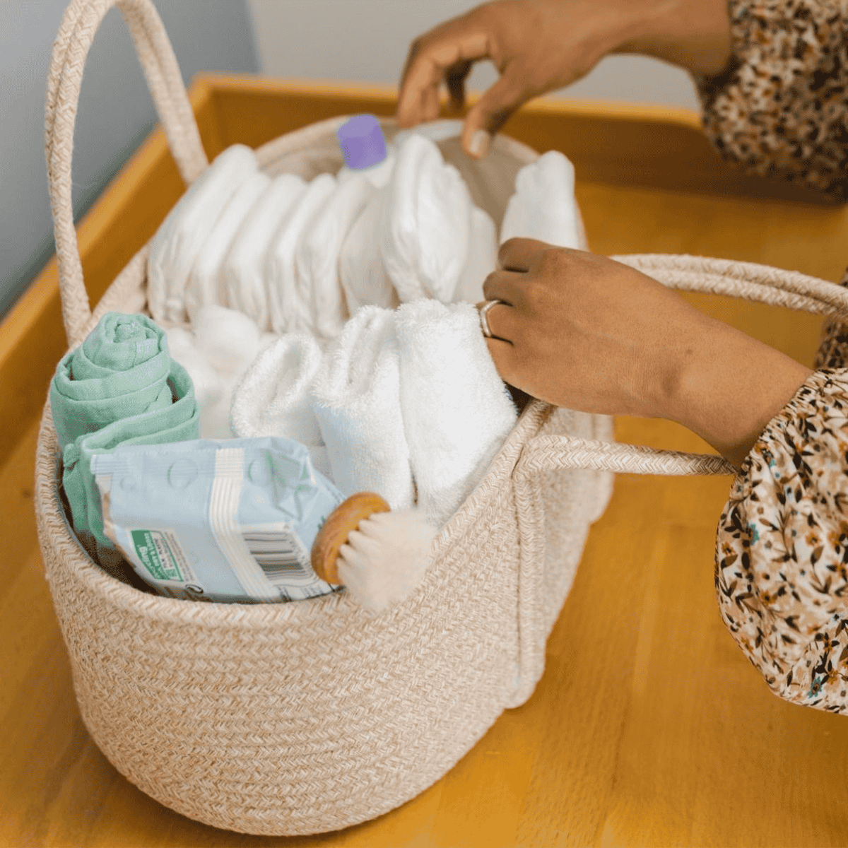 Person organizing items in a woven basket on a wooden surface