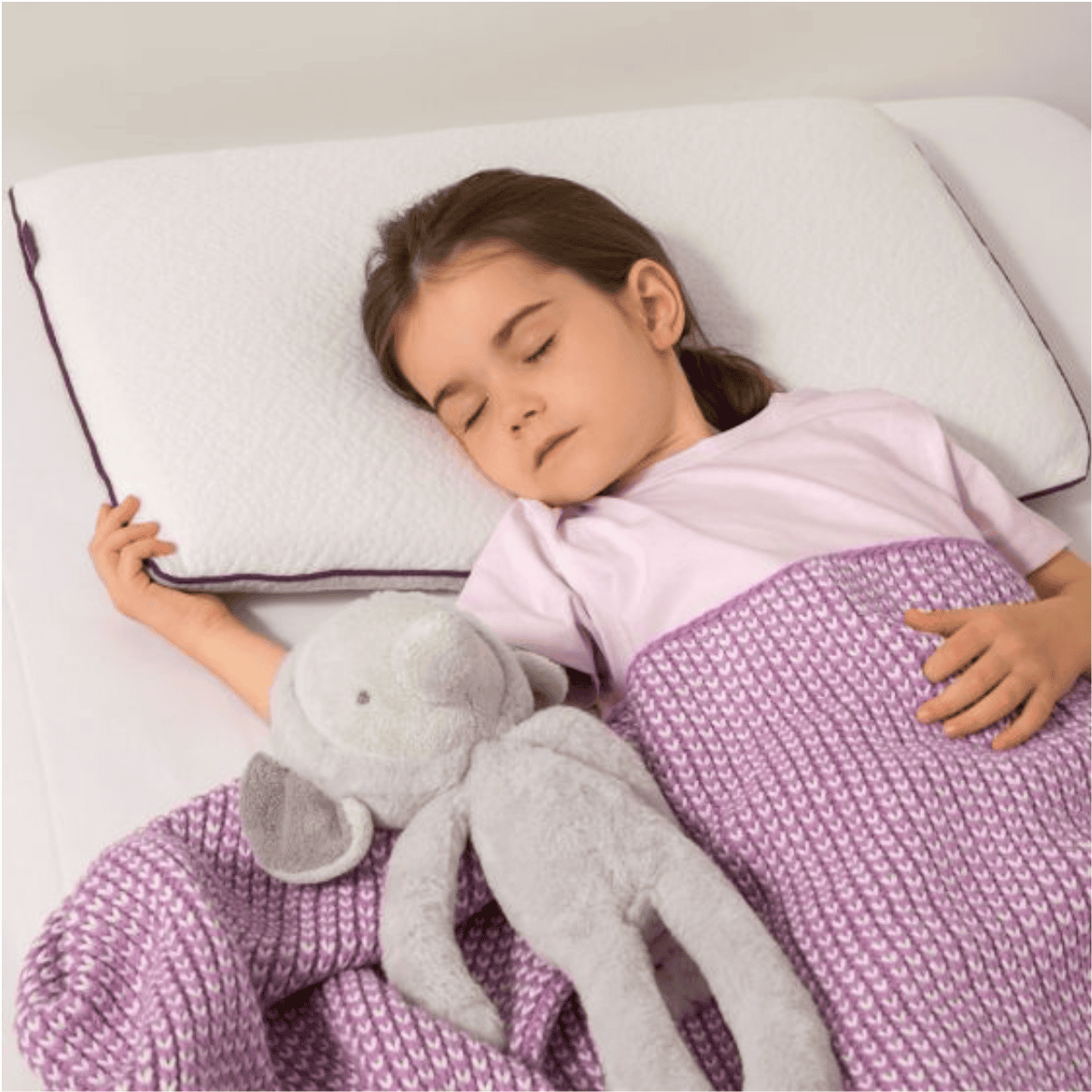Child sleeping with a purple blanket and gray stuffed elephant