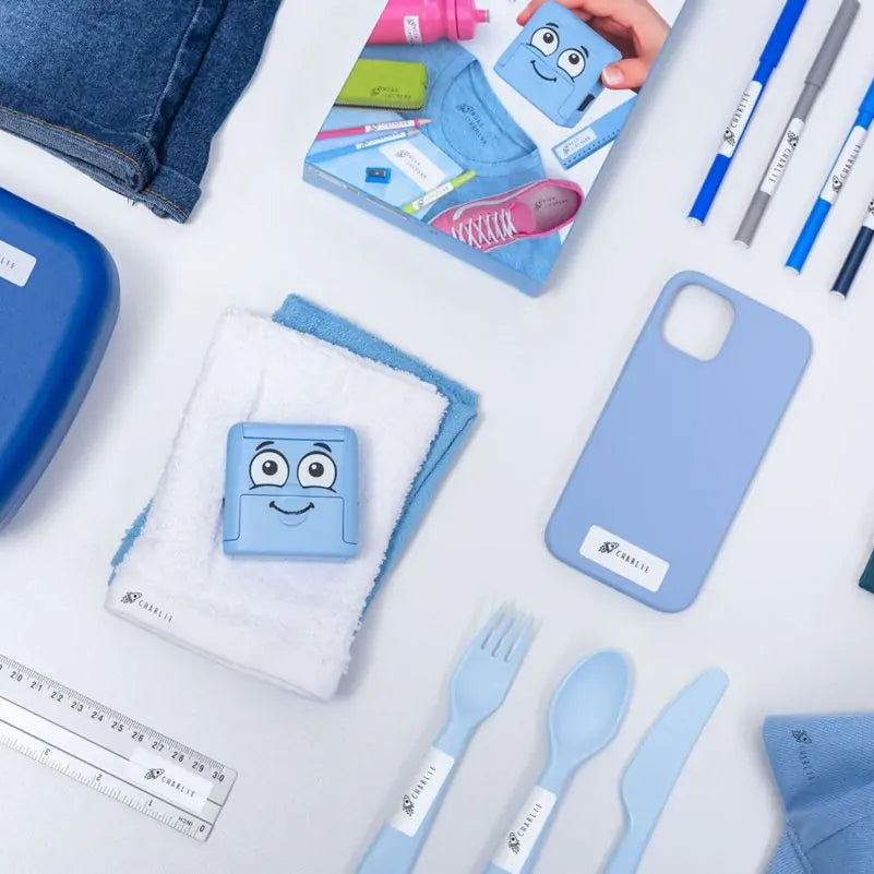 Collection of blue stationery items including phone case, lunch box, and cutlery on a white surface.
