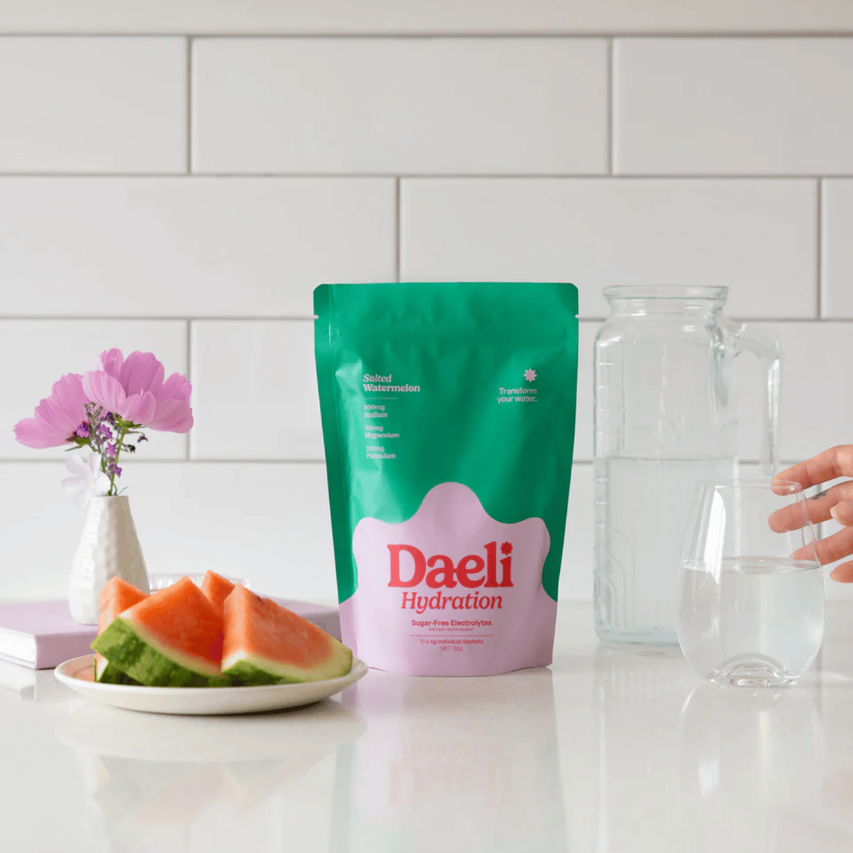 Daeli Hydration package on a kitchen counter with watermelon and a glass.