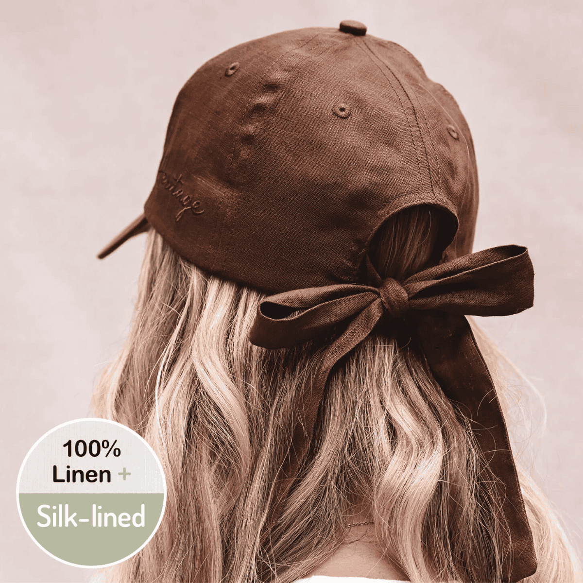 Brown linen cap with silk lining worn by a person, on a plain background