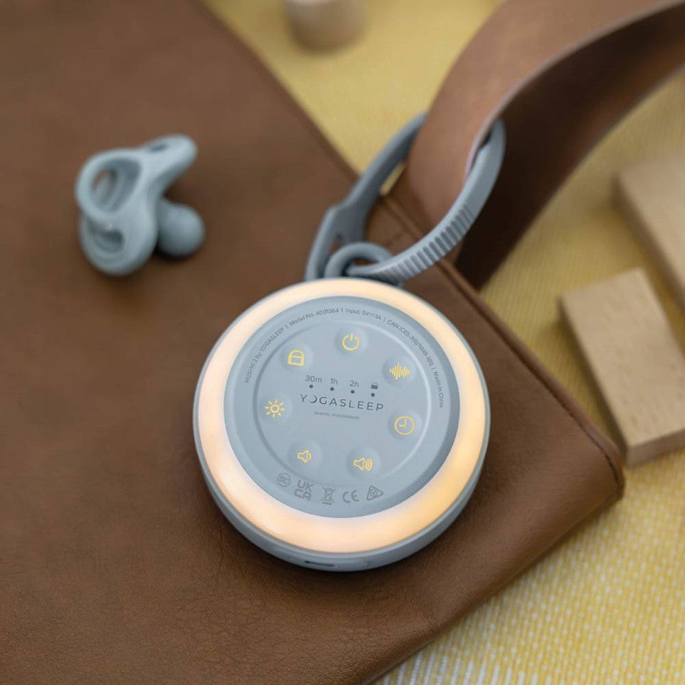 Round sleep aid device with control panel on a brown surface, accompanied by a dummy.