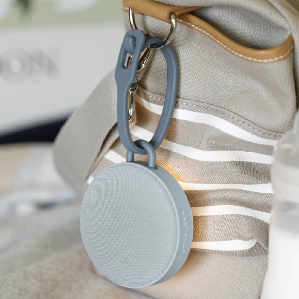 Gray keychain device attached to a beige bag with white stripes