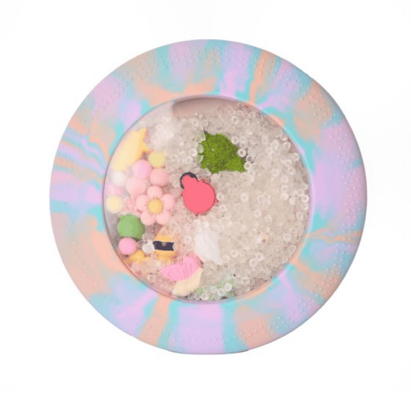 Round decorative item with colorful beads and a pink heart on a pastel marbled background