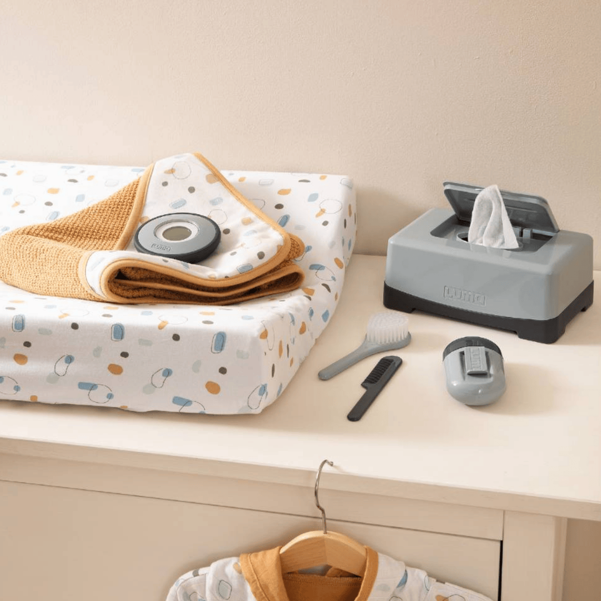 Baby changing table with baby care items including a changing pad, wipes, and a hairbrush.