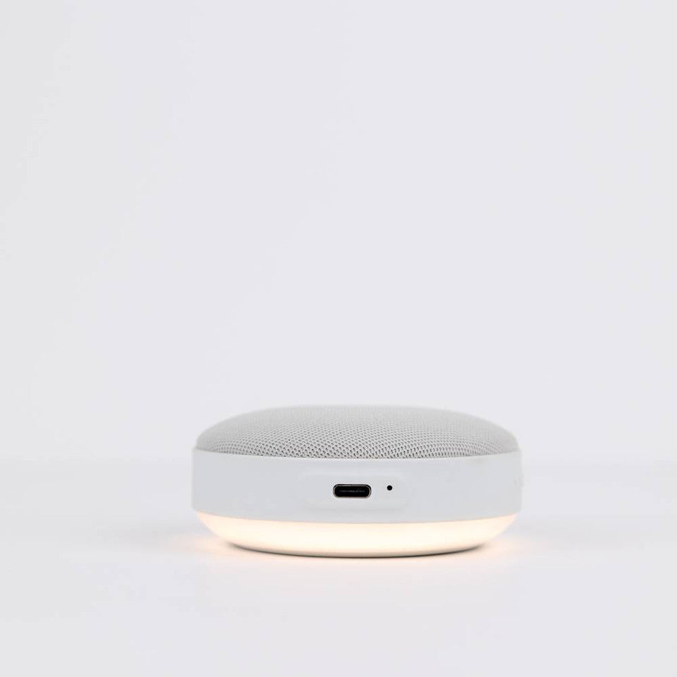 White round speaker with a glowing base on a light gray background