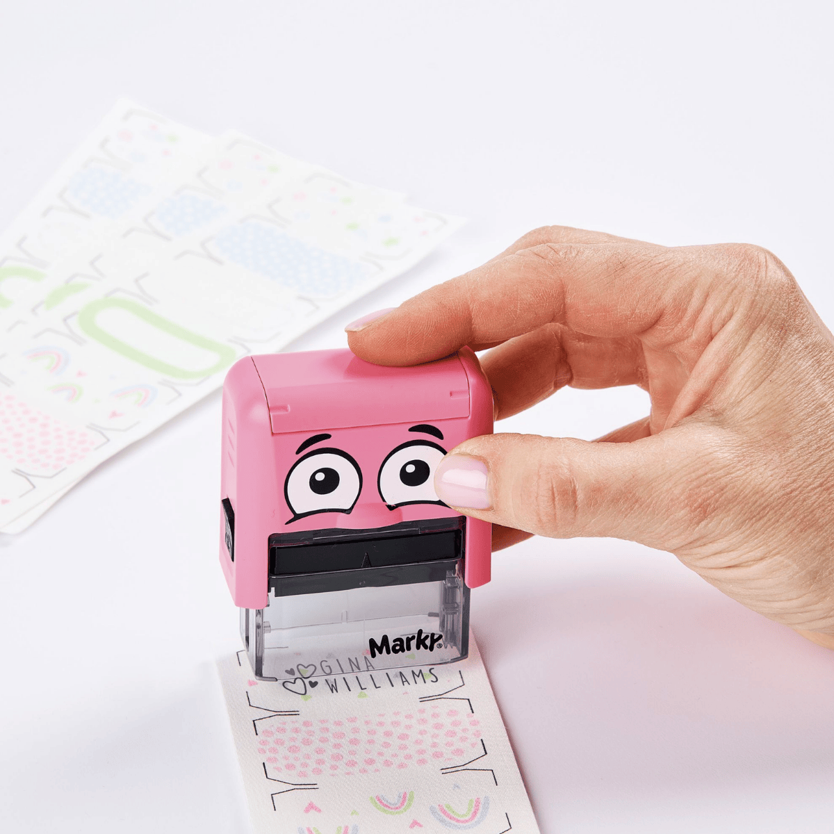 Pink emoji stamp with a hand holding it above a piece of paper.