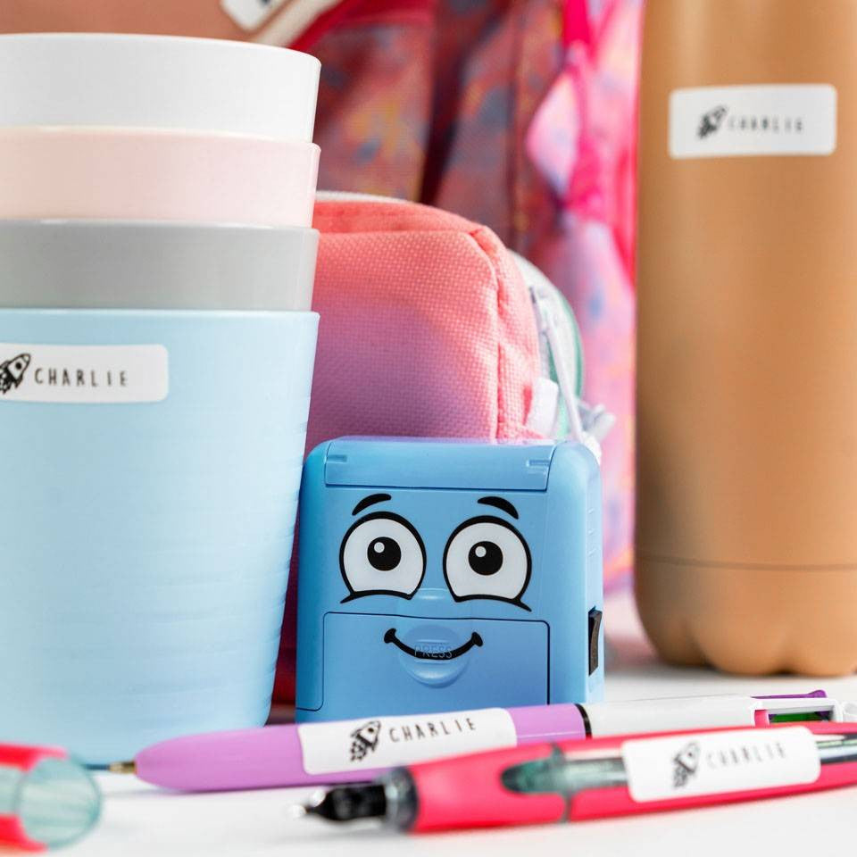 Blue cartoon-style pencil sharpener with colorful pens and containers in the background