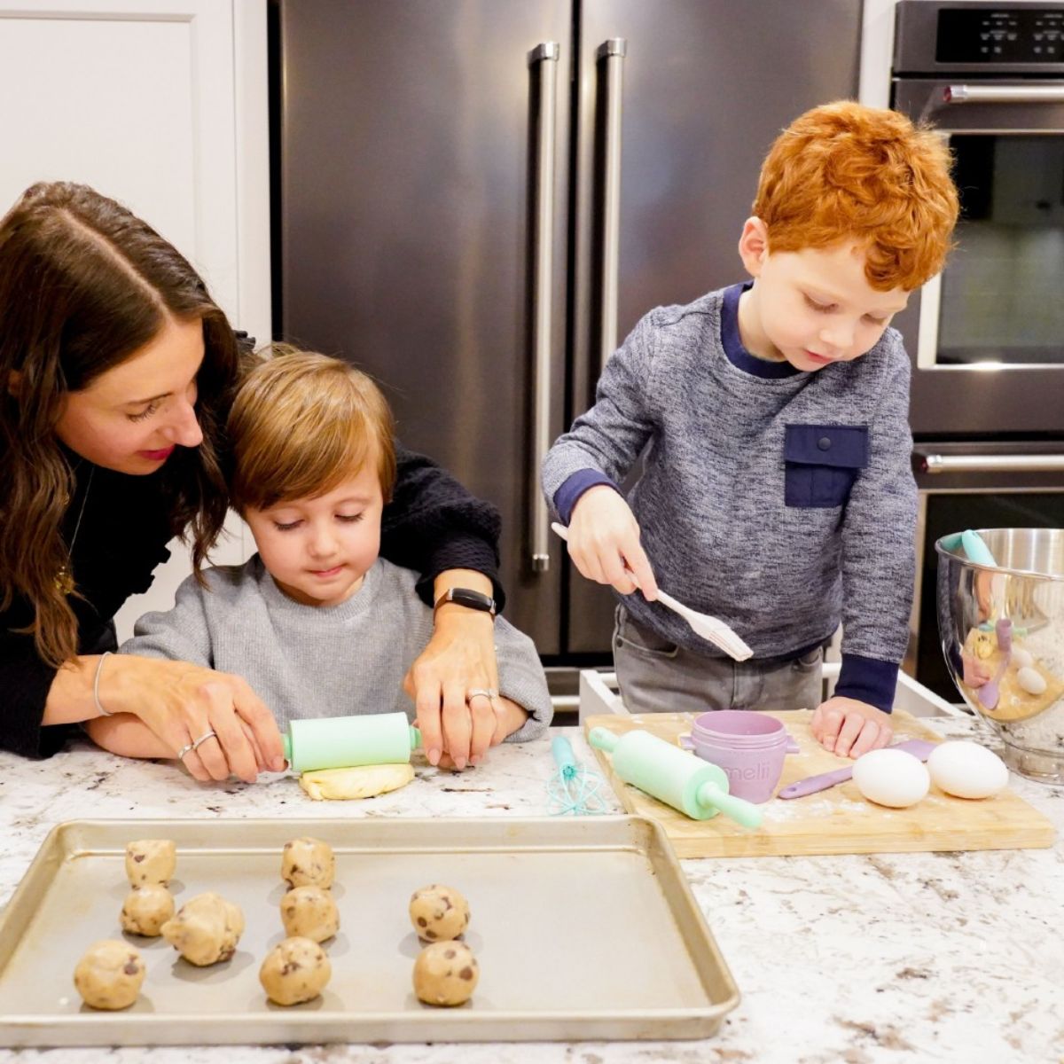 Woman and two children in a kitchen baking cookies.