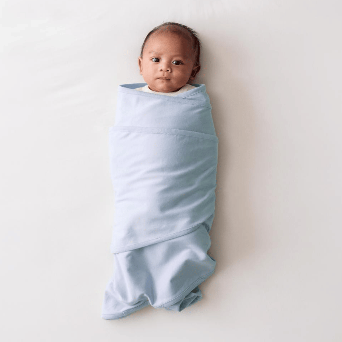 Baby wrapped in a light blue swaddle on a white background