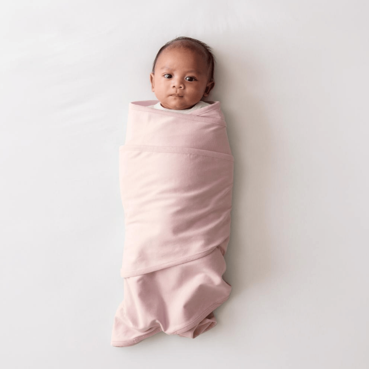 Baby wrapped in a pink swaddle on a white background