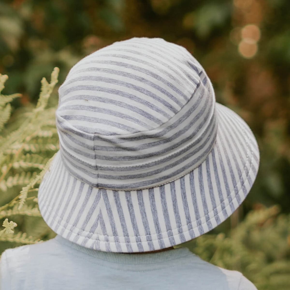Person wearing a striped bucket hat with a blurred natural background