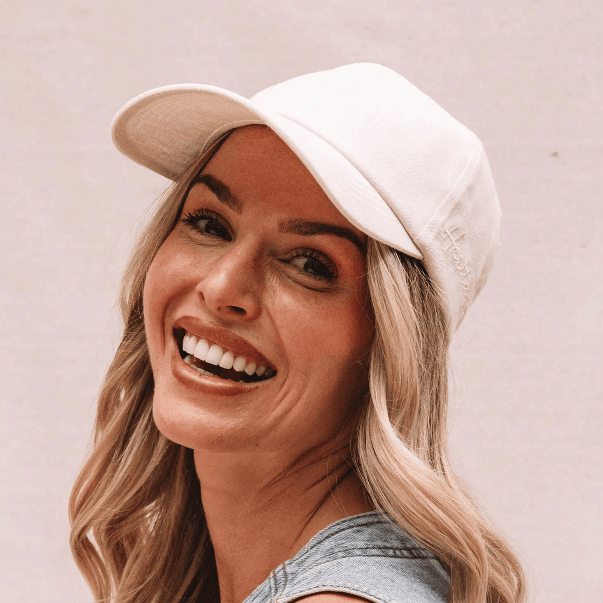 Woman wearing a white cap against a light background