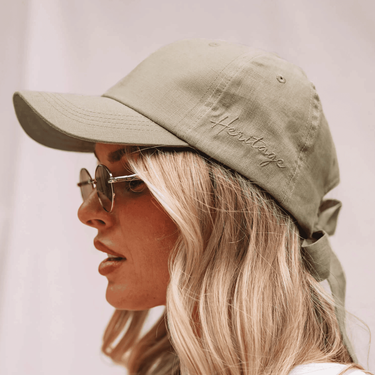 Person wearing a green cap with 'Heritage' embroidery on a plain background
