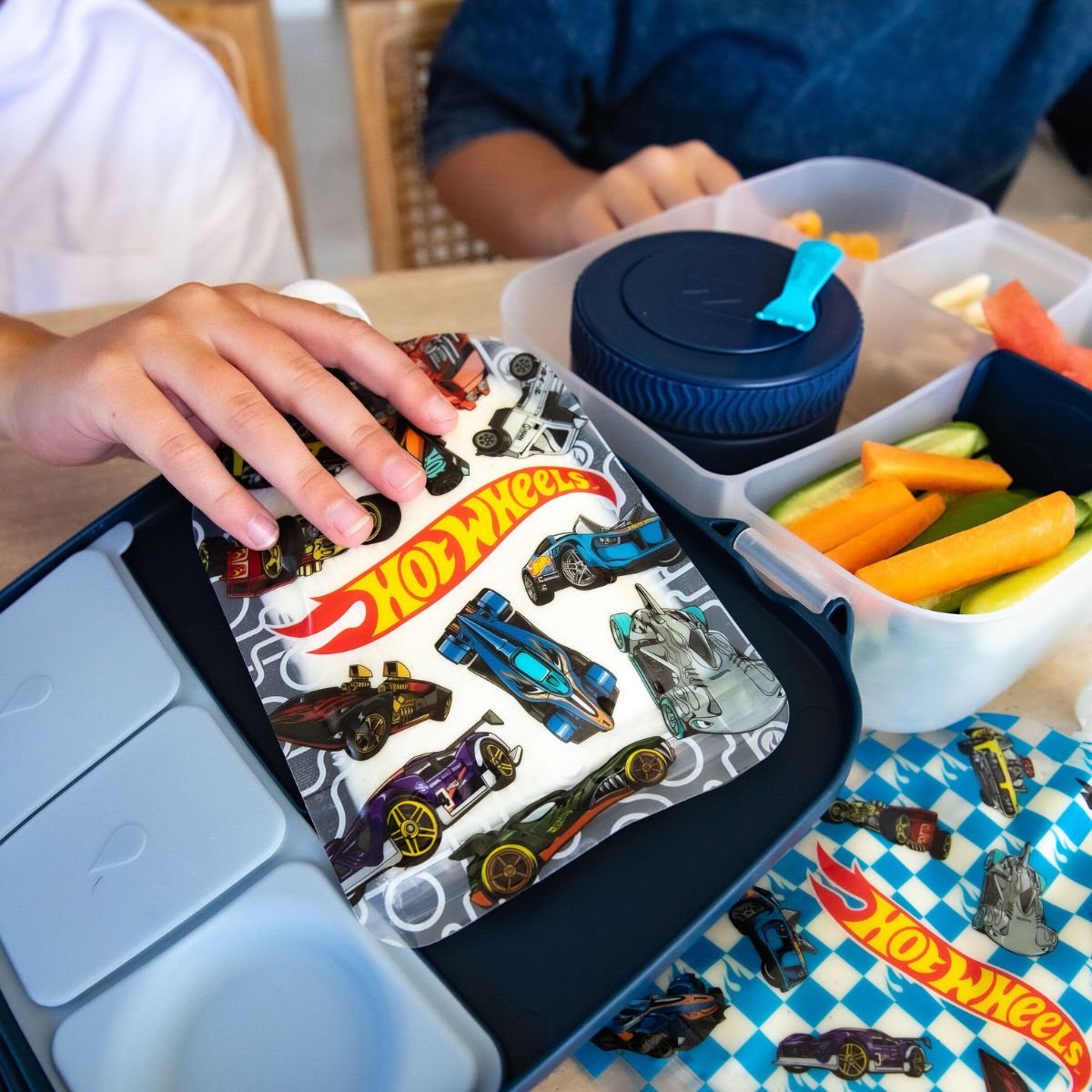 Children playing with Hot Wheels sinchie in a lunchbox with a checkered tablecloth.