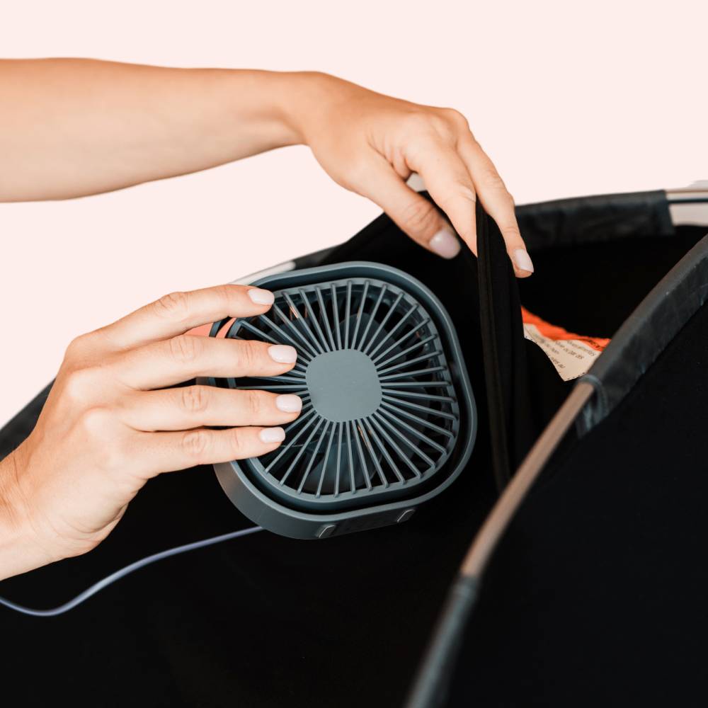 Person holding a black handheld fan with a white background