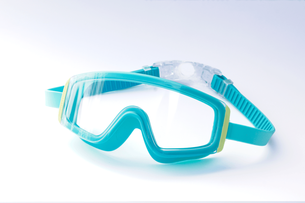 Blue Kids swim goggles with green accents on a light blue background