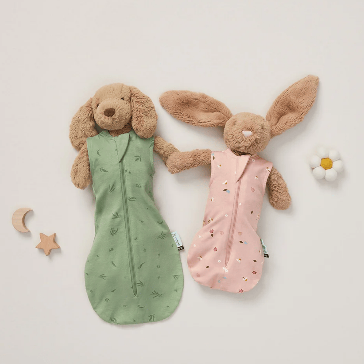 Two plush toys, one green and one pink, with animal designs on a light background.