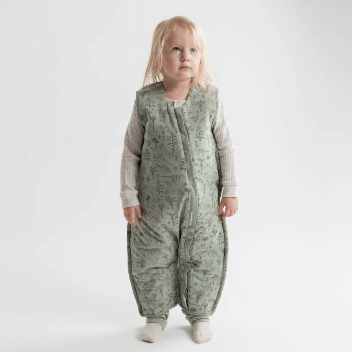 Child wearing a green patterned onesie on a white background
