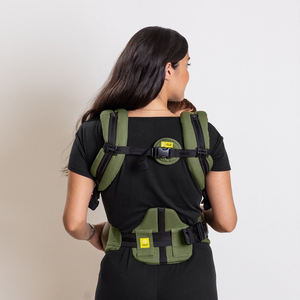 Person wearing a olive green backpack with visible branding on a plain background